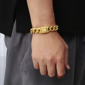 Detail of wide gold Cuban link bracelet for men with matte textured clasp on wrist