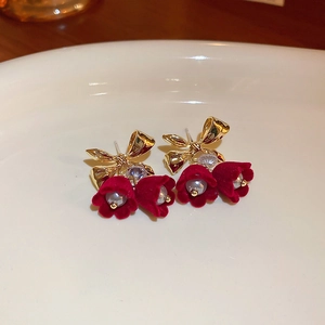 Detailed close-up of bow earrings with red flocked flowers and pearls on white ceramic