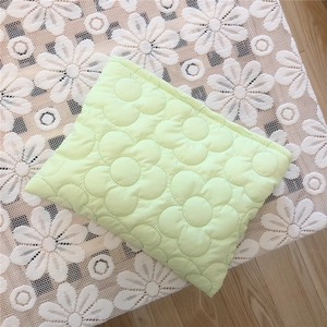 Detail of light green quilted pouch with floral embroidery on white lace background