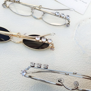 Close-up of oval metal eyewear frames with luxury rhinestone inlay in gold and silver