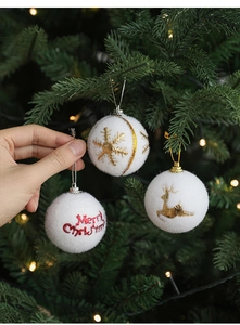 Detailed view of white flocked Christmas ball with golden elk embroidery on festive tree