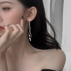 Detail of silver long star tassel earrings worn by a model for an elegant look