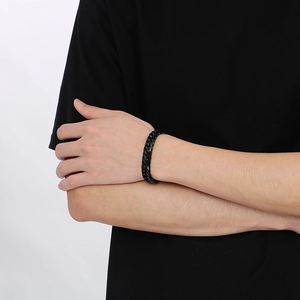 Gros plan d'un bracelet gourmette noir en acier inoxydable sur le poignet d'un mannequin