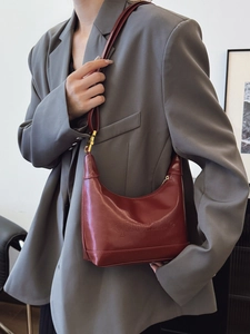Reddish brown PU leather crescent shoulder bag with gold hardware worn by model
