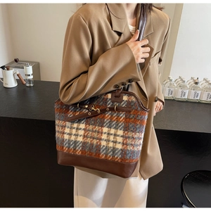 Detail shot of vintage plaid woolen fabric and brown leather stitching on tote bag
