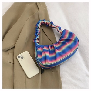 Rainbow gradient pleated shoulder bag displayed on a beige blazer with a smartphone