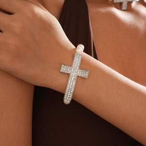 Macro shot of silver rhinestone cross pendant on elegant white pearl necklace strands