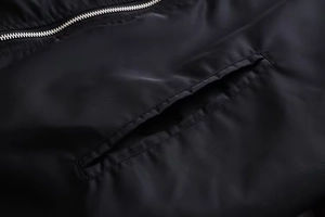 Nahaufnahme von Metallreißverschluss und genähter Tasche an schwarzer Bomberjacke