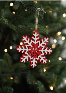 Detail of red and white layered wooden snowflake ornament hanging on a festive Christmas tree
