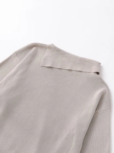 Close-up of the delicate neckline stitching on a soft light grey knitted sweater