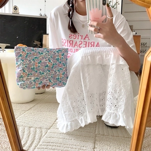 Detailed view of a purple floral cotton cosmetic bag held by a model in a cozy home setting