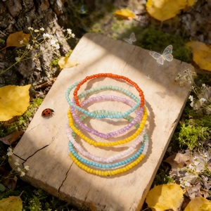 Lot de 7 bracelets en perles colorées faits main sur un plateau en bois et lumière douce