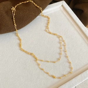 Close-up of golden double-layered beaded chain necklace with fine metallic texture