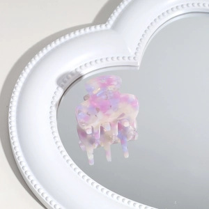 Detailed macro view of a pink and purple marbled acetate hair claw on a heart mirror