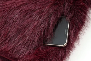 Detail shot of the deep pocket on the burgundy faux fur jacket with a smartphone inside