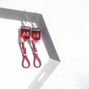 Detailed view of creative blood bag earrings with red fluid and AB group labeling