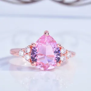 Macro d'une bague en or rose avec pierre rose en forme de poire et zircons blancs
