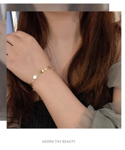 Nahaufnahme eines minimalistischen goldenen Scheibenarmbands am Handgelenk für Damen