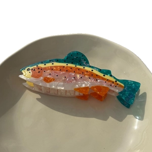 Pince à cheveux en forme de poisson coloré en acétate marbré dans un bol beige
