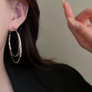 Détail de boucles d'oreilles créoles doubles argentées avec finition polie sur l'oreille