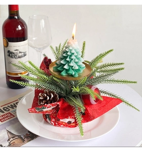 Detail of Christmas tree candle with pine cones and berries on a red fabric base
