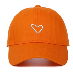 Detail of vibrant orange baseball cap with white embroidered heart on cotton twill fabric