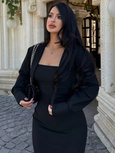 Gros plan sur l'ensemble robe noire ajustée avec collier trèfle et sac à chaîne