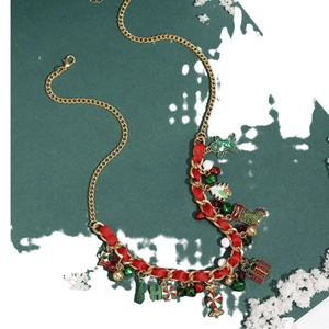 Christmas necklace with gold chain, red ribbon and enamel ginger man charms on snow backdrop