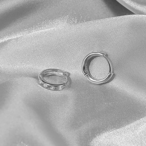 Close-up of S925 sterling silver hoop earrings with zircon pavé on silk fabric