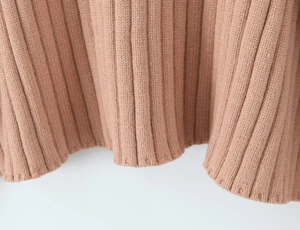 Close-up of pink knit fabric showing vertical ribbed texture and hem stitching detail