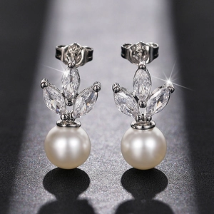 Macro detail of marquise-cut zircons and high-luster white pearl drop on silver earrings