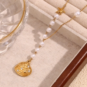 Detail of 18K gold-plated necklace with star charm, faux pearls and crystal shell pendant