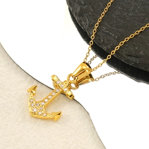 Collier ancre dorée serti de zircons brillants présenté sur un décor de luxe