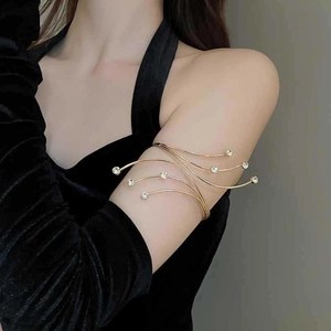 Detailed view of elegant gold arm cuff with sparkling zircon accents on a velvet dress