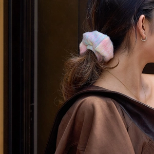Dettaglio di un elastico per capelli in maglia sfumata con colori macaron su una coda