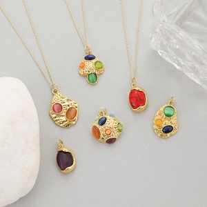 Gold necklaces featuring colorful mushroom pendants and cat eye stones on a natural stone base
