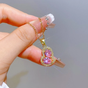 Macro shot of gold heart necklace with pink pear-shaped gems and sparkling diamonds