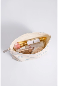 Detail of a large capacity cream cotton makeup bag with blue bow prints and zipper