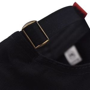 Detail of black cotton baseball cap with adjustable strap and vintage bronze metal buckle