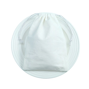 Minimalist white cotton drawstring pouch for jewelry storage on a ceramic plate
