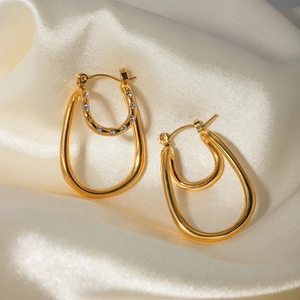 Orecchini a doppia curva placcati in oro 18k con zirconi bianchi su sfondo di seta