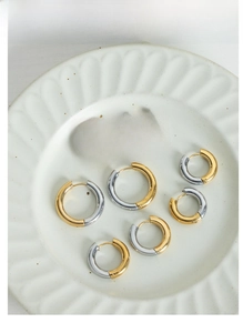 Detail of two-tone gold and silver hoop earrings in various sizes on a ceramic plate