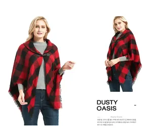 Detail view of red plaid cape featuring fringe edges and leather toggle horn button closure