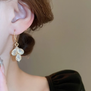 Close-up of golden teardrop cat-eye stone petal earrings with sparkling rhinestones