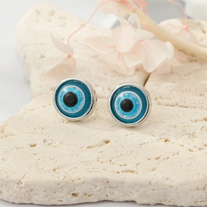 Macro view of blue resin Evil Eye stud earrings on a textured stone surface