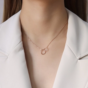 Interlocking double circle necklace in rose gold finish on model wearing a white suit