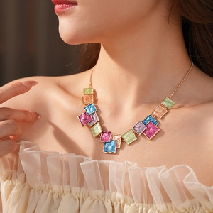 Detail view of a colorful enamel square pendant necklace on a model with gold chain