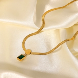 Detail of 18K gold stainless steel snake chain necklace with green zircon pendant on silk