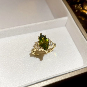 Detail of a 14K gold plated ring with marquise green stone and white side gems