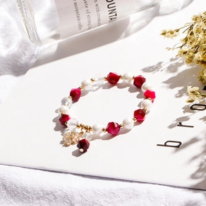 Close-up of handmade baroque pearl bracelet with red beads and golden flower charm